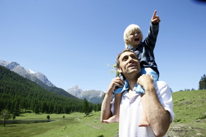 Vater mit kleinem Jungen auf den Schultern beim Wandern in den Bergen