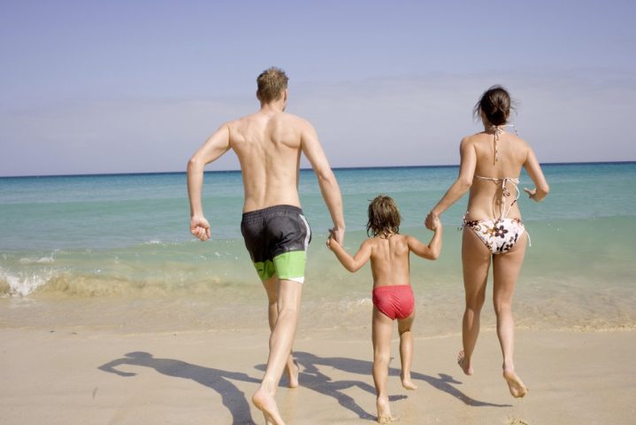 Mutter, Vater und Kind laufen händchenhaltend ins Meer
