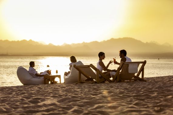 Urlauber chillen bei Sonnenuntergang am Strand