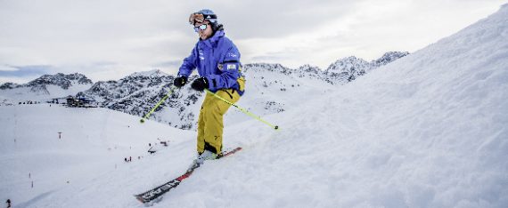 Mann auf einer Skipiste mit warmer Skikleidung,Helm und Sonnenbrille