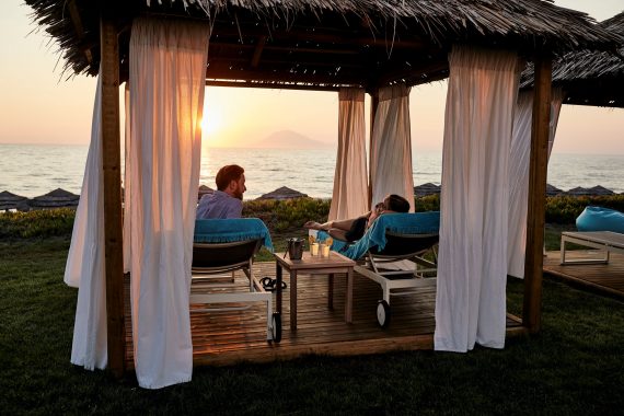 Pärchen auf Daybed bei Sonnenuntergang im ROBINSON Club Kyllini Beach, Peloponnes, Griechenland