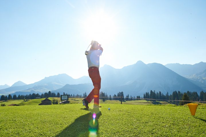 Golfspieler beim Abschlag vor Bergpanorama