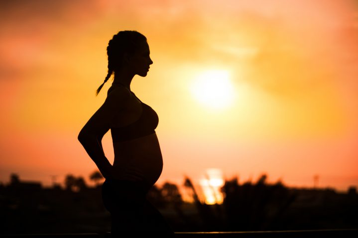 Schwangere Frau beim Sonnenuntergang