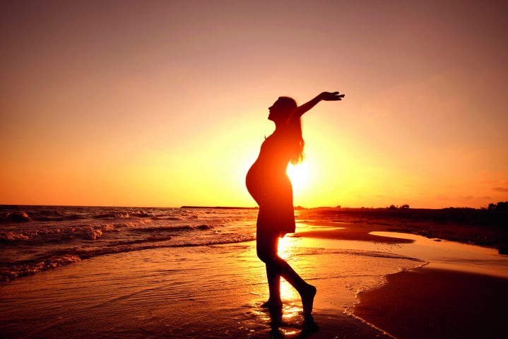 Schwangere Frau am Strand bei Sonnenuntergang