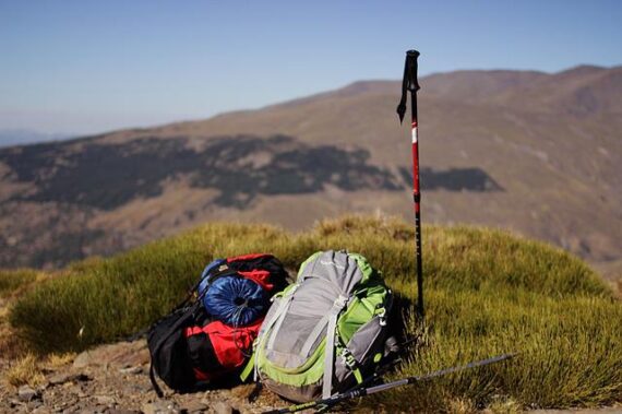 Trekking-Ausrüstung Rucksäcke und Wanderstock vor einem Tal
