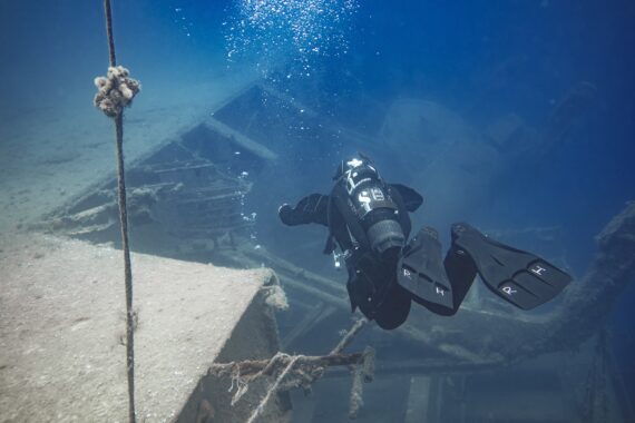 Das alte Schiffswrack Zenobia mit einem Taucher, der gerade darauf zu schwimmt von hinten