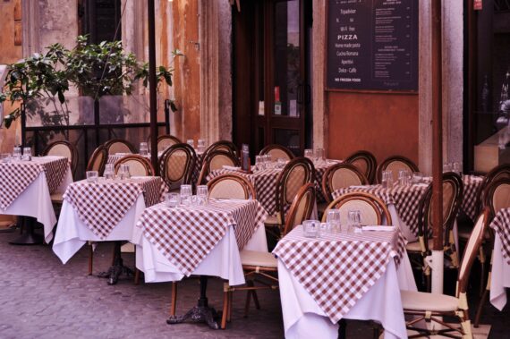 Ein italienisches Restaurant mit braun weiß karierten Tischdecken vor einer rötlichen Wand
