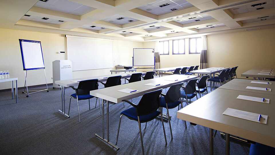 Konfernzraum mit Tischen, Flipcharts und Leinwand