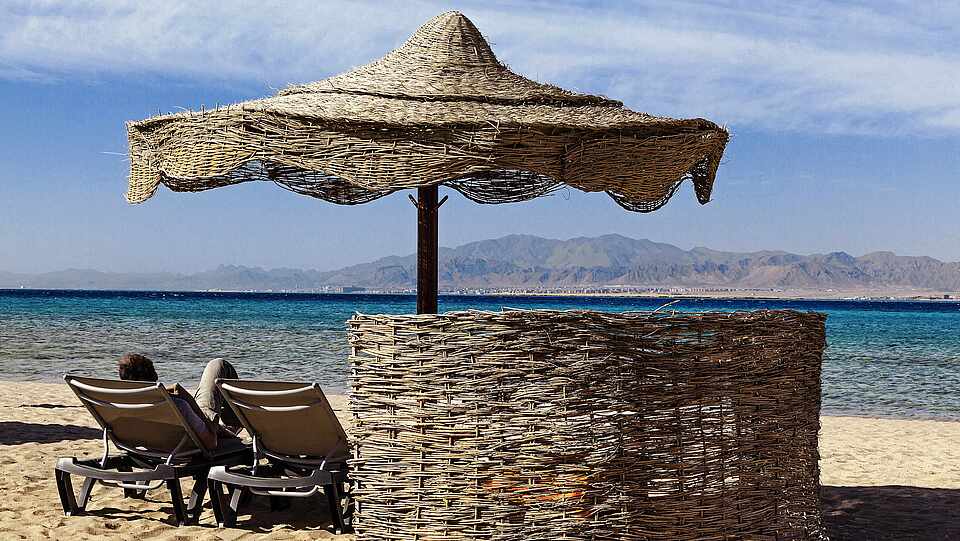 Sonnenliegen mit Schirm und Sichtschutz am Meer