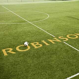 Ein Mann schießt einen Fußball über den Schriftzug von ROBINSON