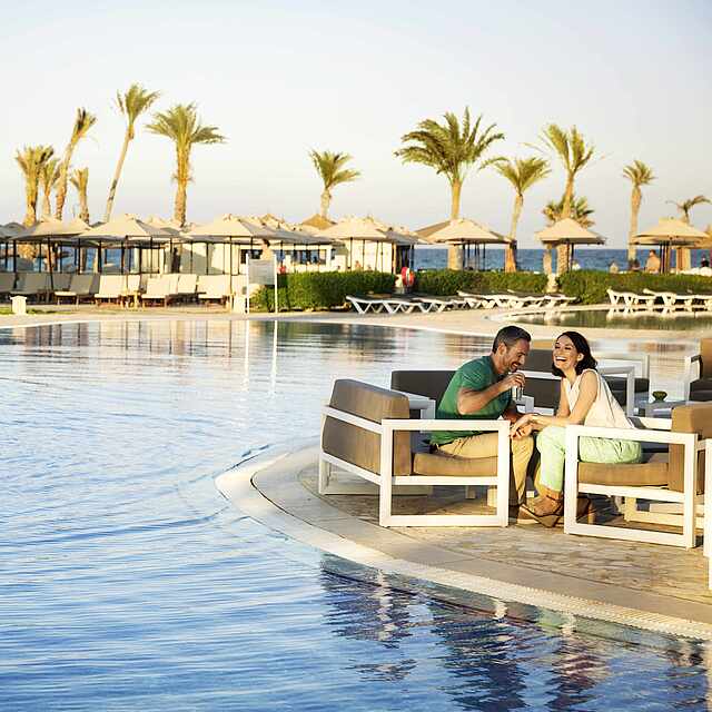 Poolbar in einzigartiger Kulisse im ROBINSON CLUB DJERBA BAHIYA Paar sitzt gemeinsam in Sesseln an der Poolbar und unterhält sich