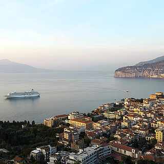 Blick von Oben auf eine Stadt am Meer, großes Schiff im Wasser