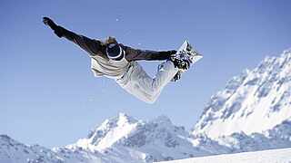 Snowboarder springt mit seinem Board in den Bergen in die Luft