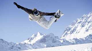Snowboarder springt mit seinem Board in den Bergen in die Luft