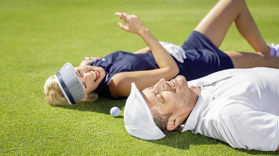 Paar liegt auf dem Green beim Golf spielen