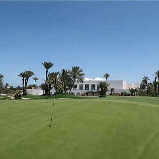 Golfplatz unter Palmen mit weißem Gebäude