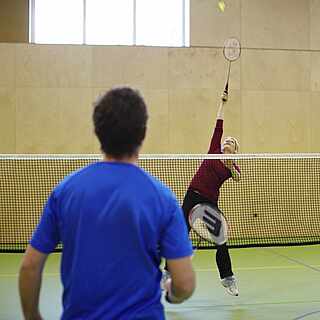 Zwei Gäste spielen Badminton in einer Halle