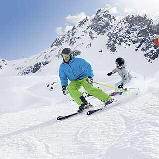 Eine Frau und ein Mann fahren auf Skiern die Piste hinunter
