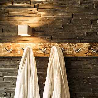 Man sieht eien Sauna und vor der Sauna hängen 2 Bademäntel