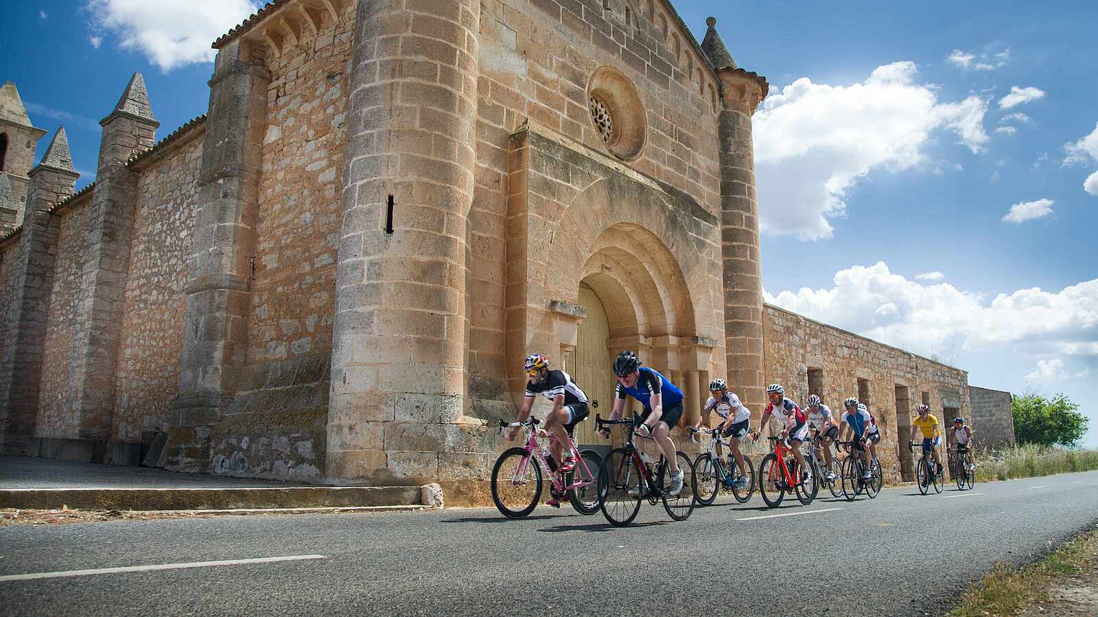 Eine Gruppe von Rennradfahrer fährt an einer alten Kirche entlang.