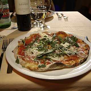 Ein Teller mit einer Pizza auf einem eingedeckten Tisch