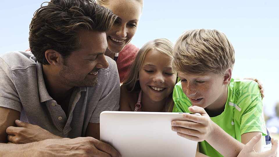 Familie sitzt vor dem Tablet und informiert sich über die ROBINSON Apps