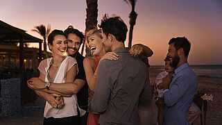 Menschen tanzen und lachen am Strand 