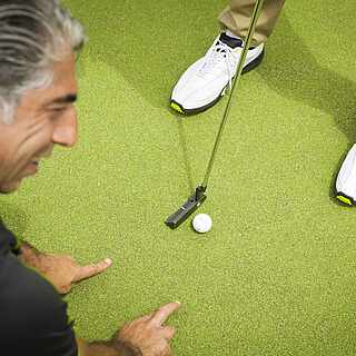 Golflehrer erklärt am Boden einen Golfschlag
