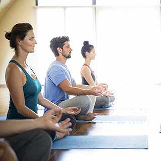 Gruppe bei der Meditation auf Fitnessmatten