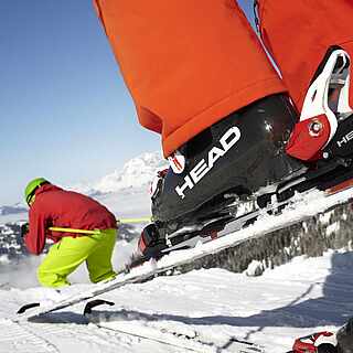 Bunt gekleideter Skifahrer mit Skiern und Skistöcken auf der Piste