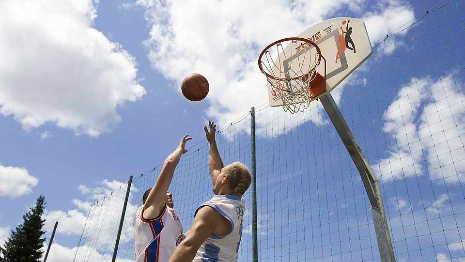 Zwei Gäste spielen Basketbakk und springen zum Korb hoch