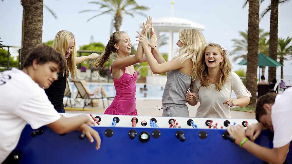 Vier Mädchen gewinnen gegen zwei Jungs im Tischkicker spielen