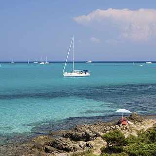 Türkises Meer mit kleinen Booten unter blauem Himmel